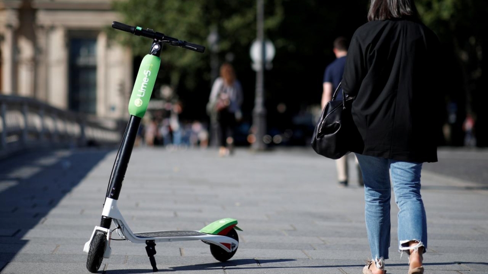 FILE PHOTO: A woman walks past a dock-free electric scooter Lime-S by California-based bicycle sharing service Lime displayed on their launch day in Paris
