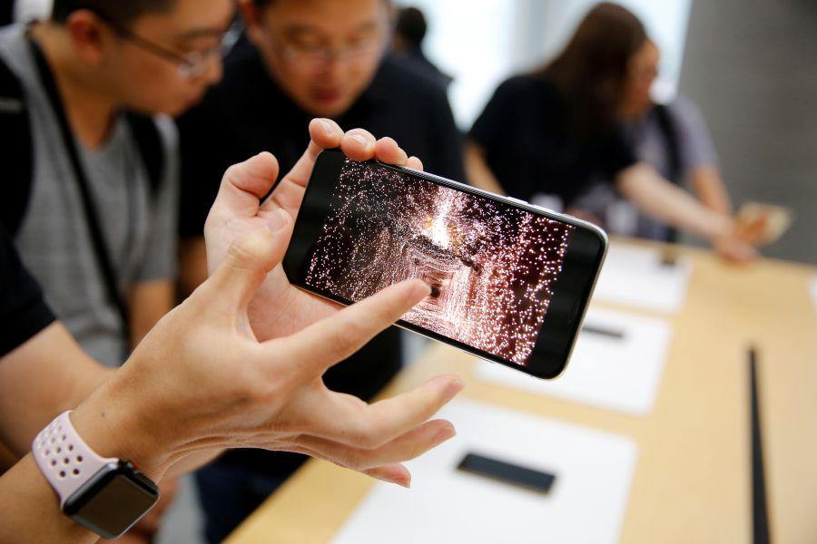 People handle the new Apple iPhone XS and iPhone XS Max during a media tour at an Apple office in Shanghai