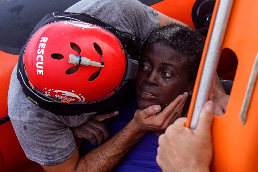A crew member of NGO Proactiva Open Arms rescue boat embraces African migrant in central Mediterranean Sea