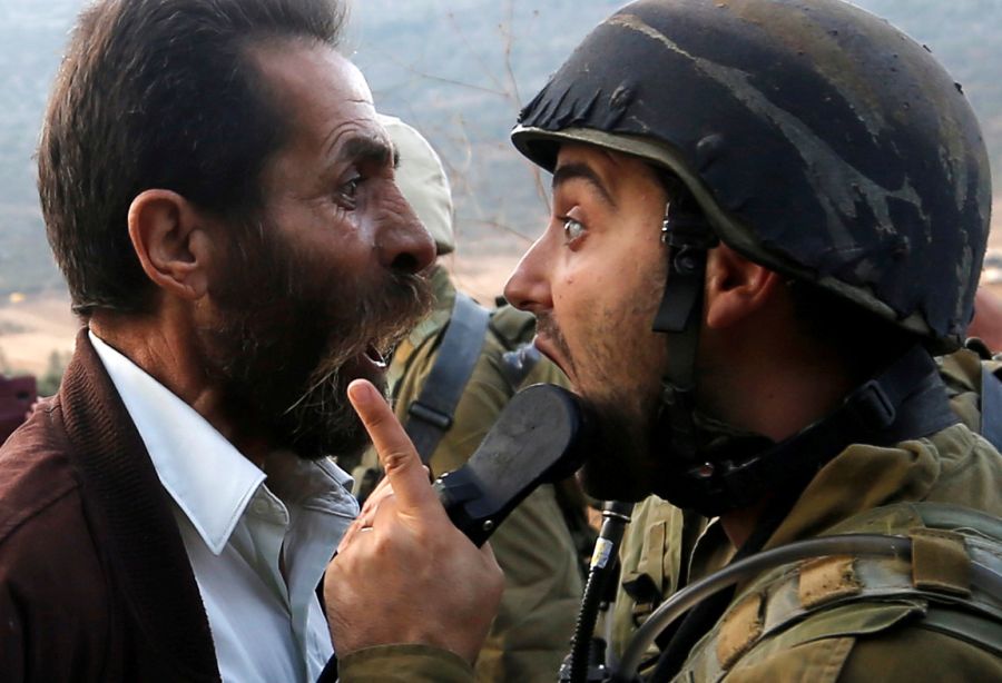 Palestinian man argues with an Israeli soldier during clashes over an Israeli order to shut down a Palestinian school near Nablus in the occupied West Bank